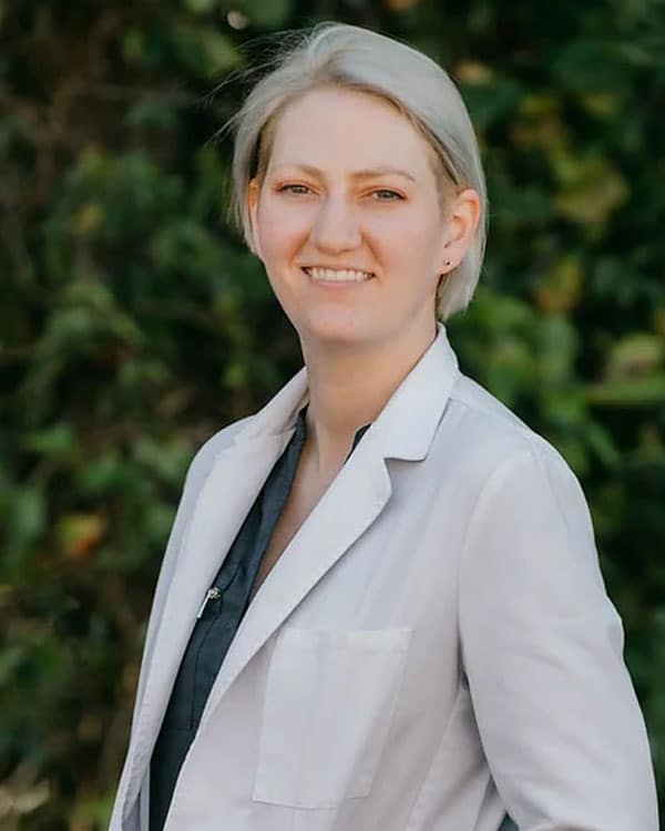 A woman in a white coat, she is a compassionate vet offering in home euthanasia services.